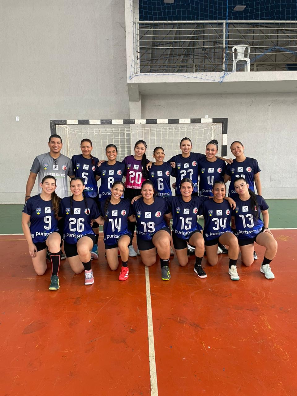 Equipe feminina de handebol da Universidade Nilton Lins posada na quadra dos JUBs 2026, ao lado do técnico