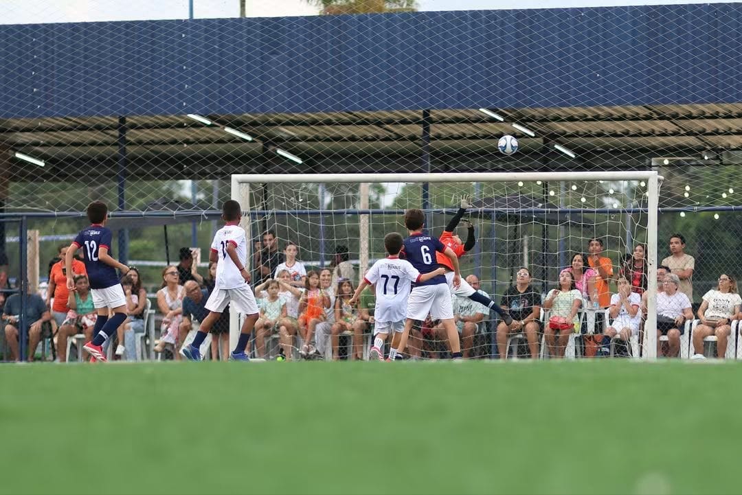 Goleiro da PSG Academy Manaus se estica para defender a bola em jogo de formação com arquibancada cheia